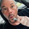 Man in car using electric razor.